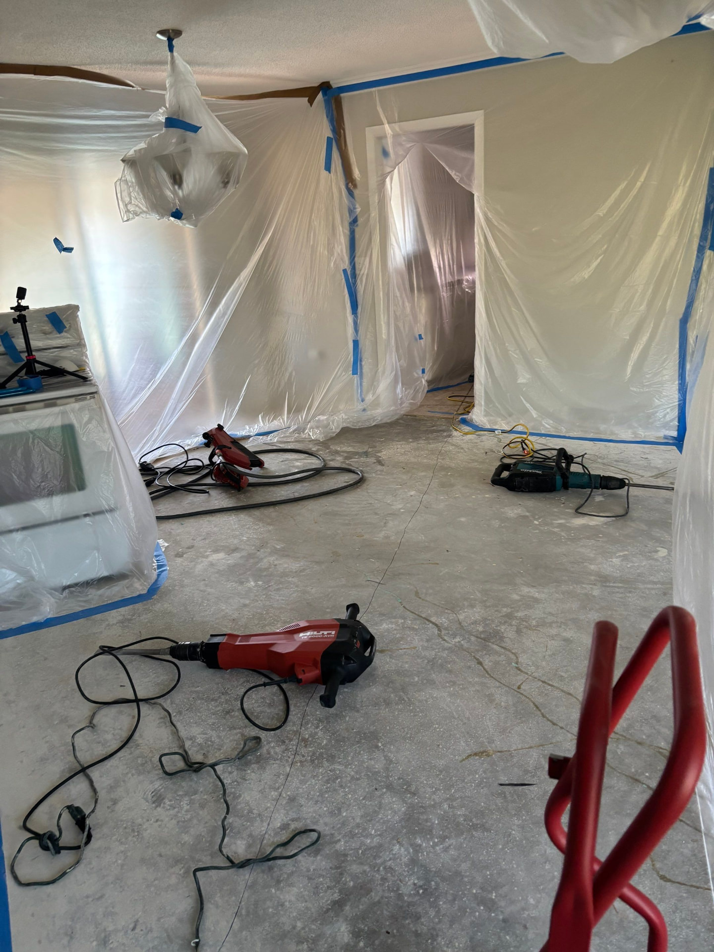 Interior work area fully contained with plastic sheeting over walls, doorway, and ceiling