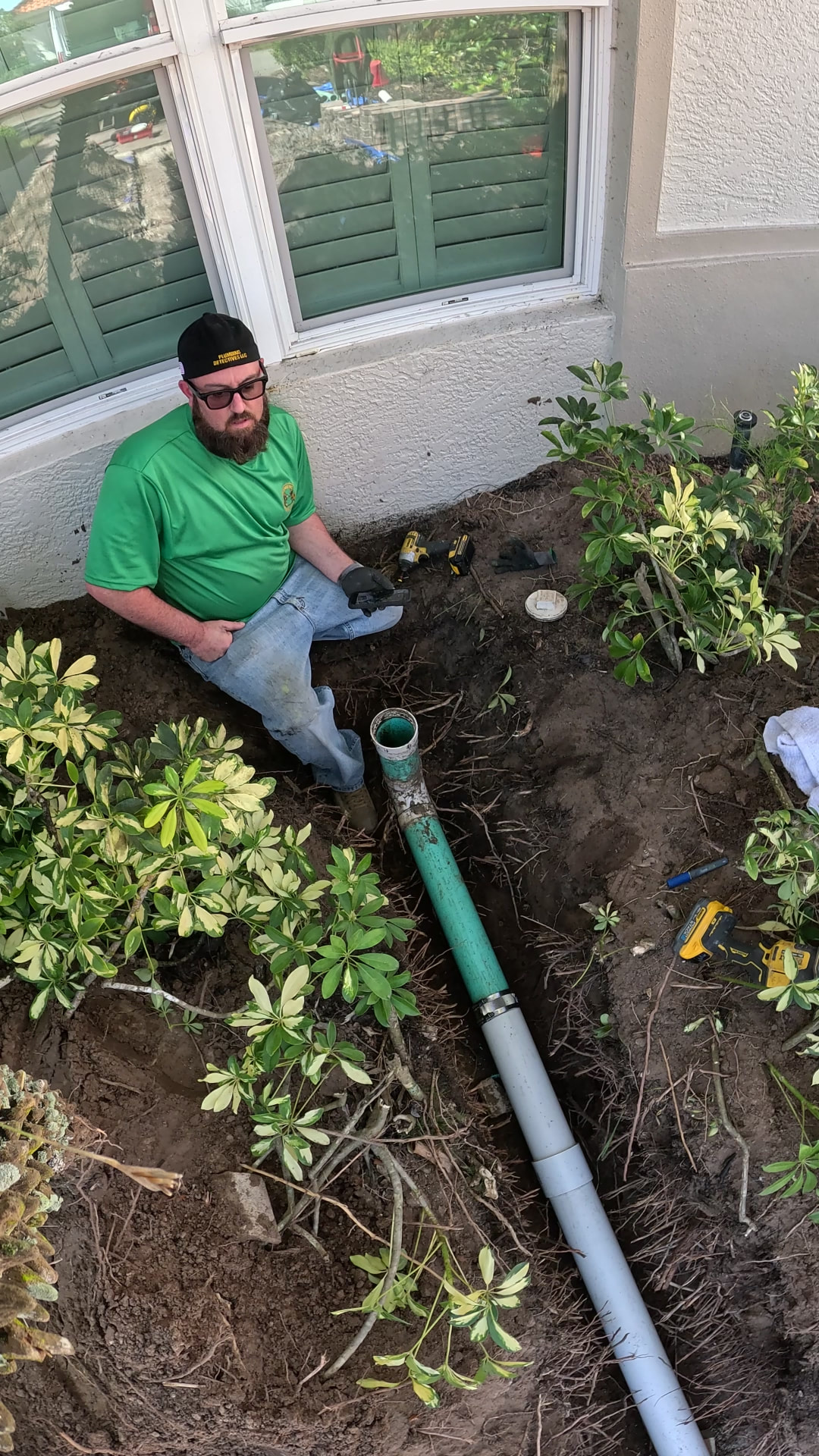 Plumber joining the remaining original sewer pipe to new PVC with a banded shielded coupling in a hand-dug trench