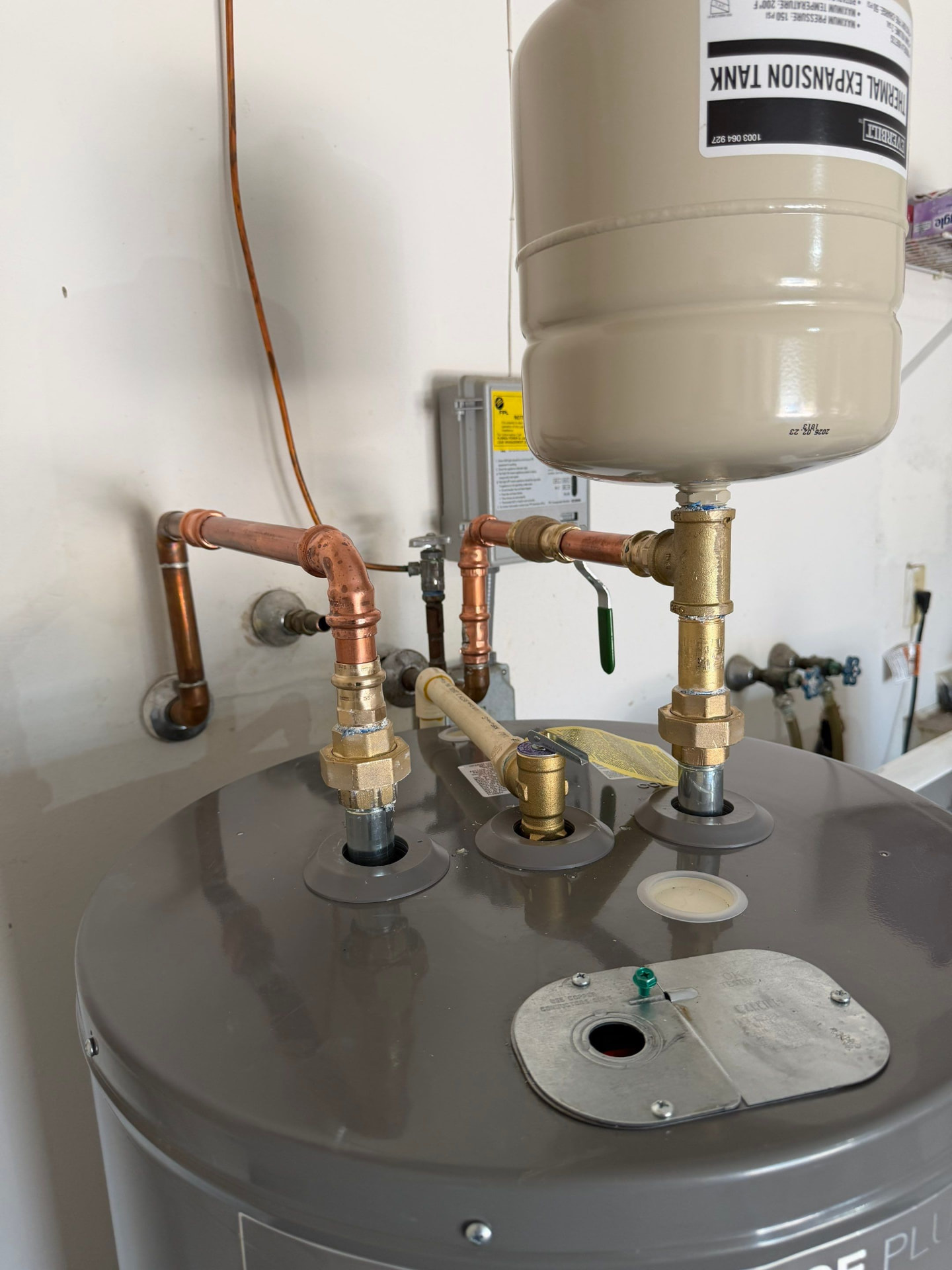 Correct thermal expansion tank installation on a copper water heater system — tank mounted on the cold side with brass unions and shutoff valve