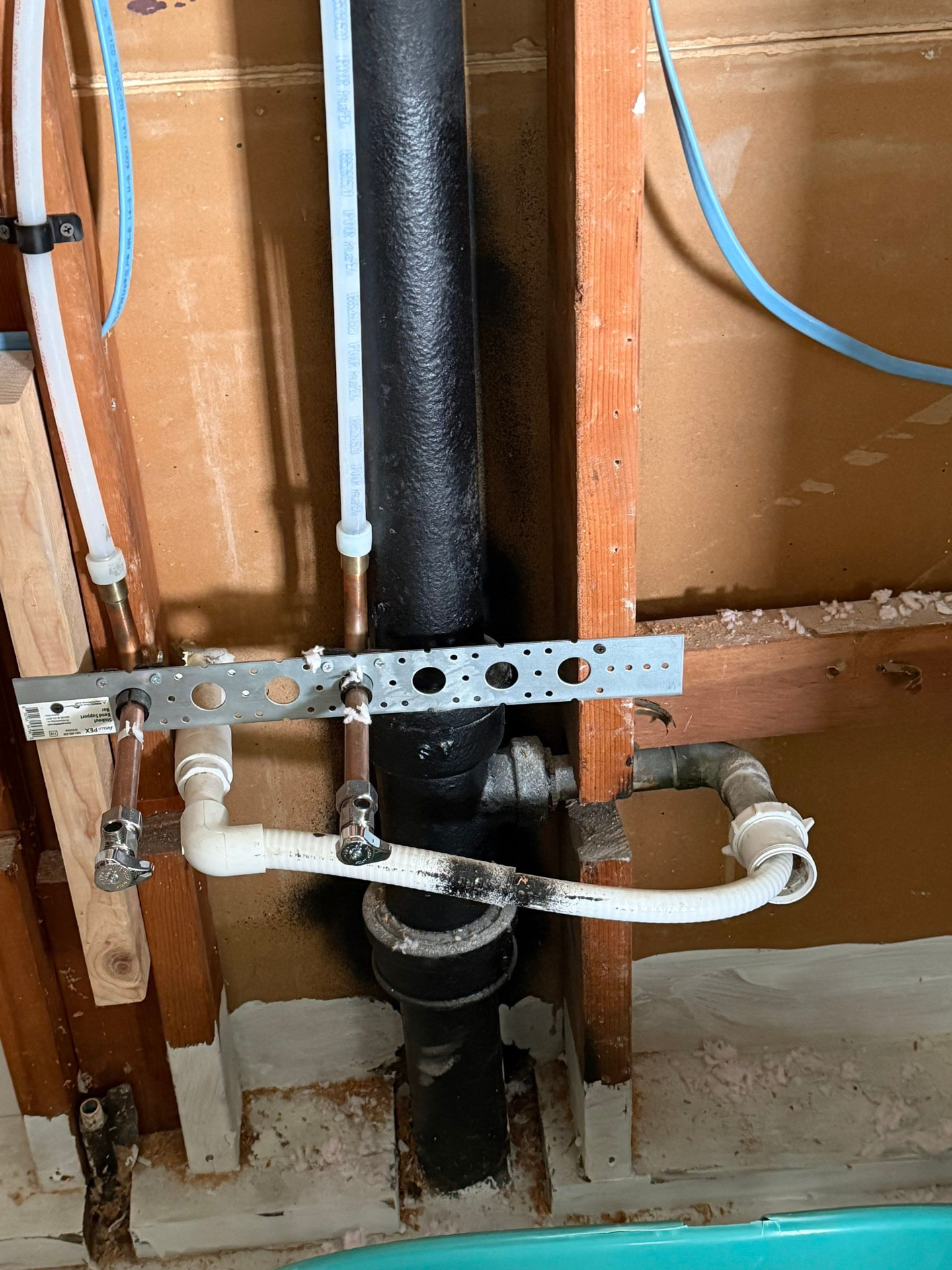 New PEX and copper lavatory supply stub-outs installed alongside an original cast-iron drain stack