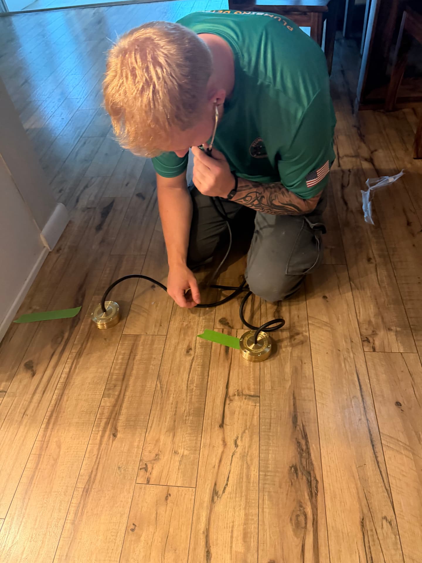 Technician placing geophones on a taped water line while compressed air agitates the leak to amplify the sound