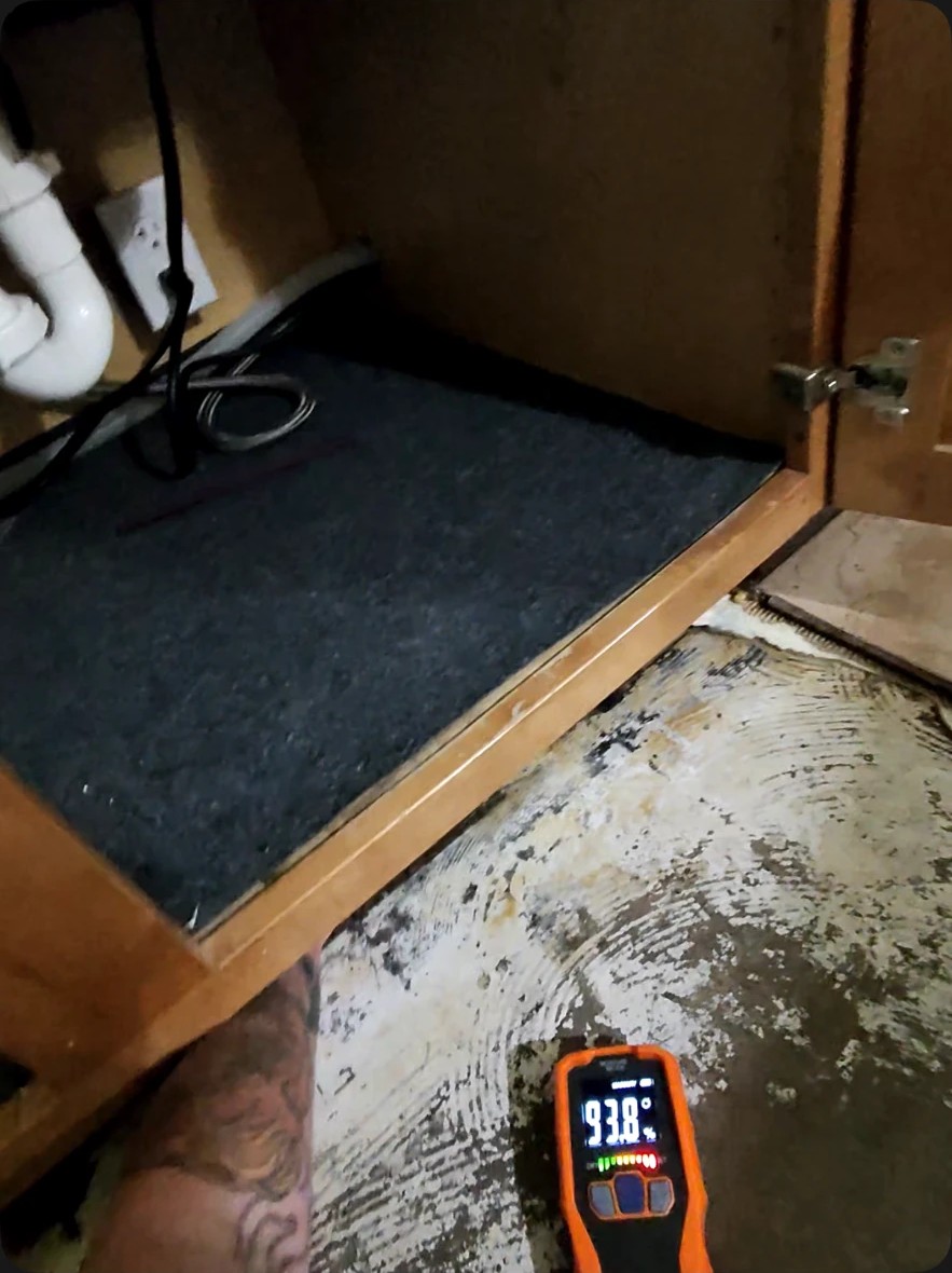 Moisture meter reading 93.8 percent on a slab beneath a sink cabinet during slab leak detection