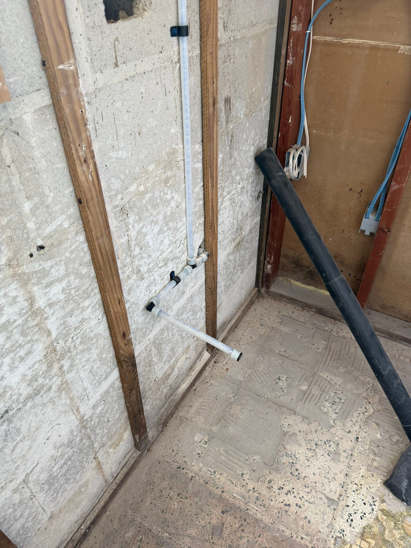 New water supply line routed down a concrete block wall to fixture rough-in height