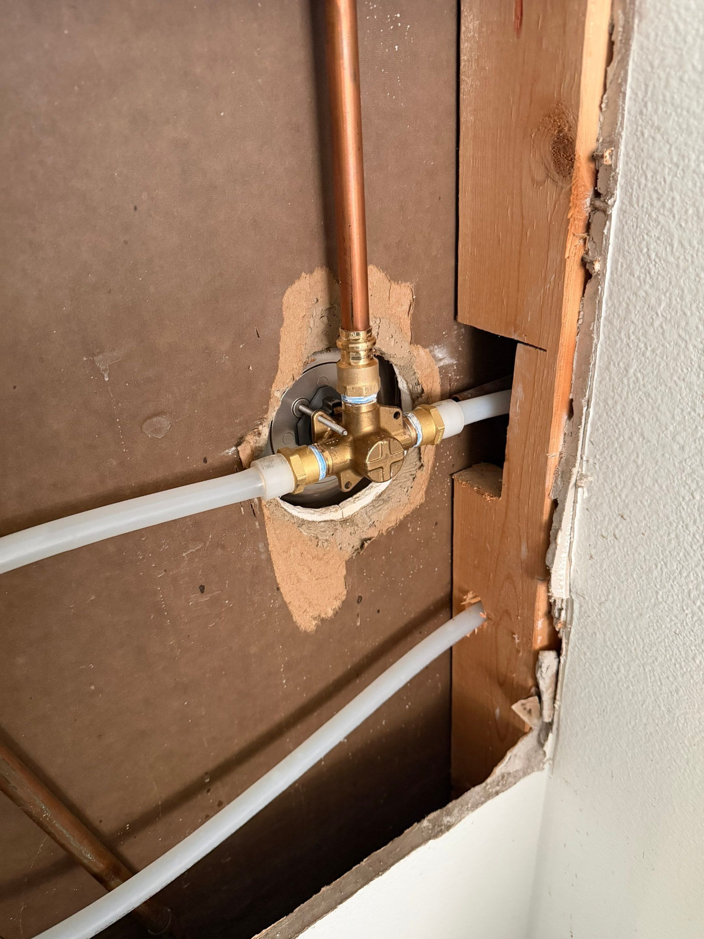 Shower mixing valve with new PEX hot and cold connections made through a minimal drywall access cut
