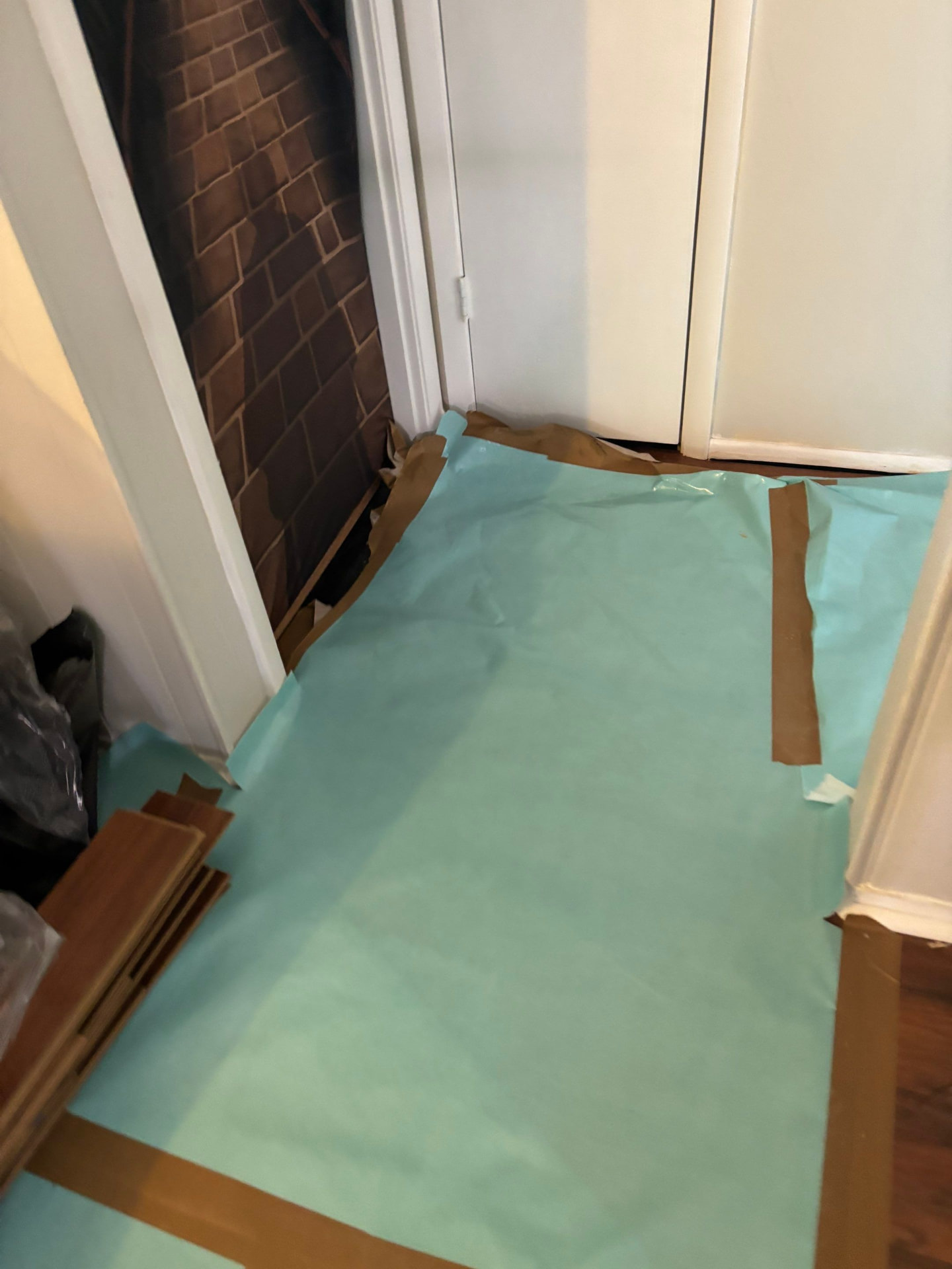 Protective floor covering taped down along the baseboards in the work area