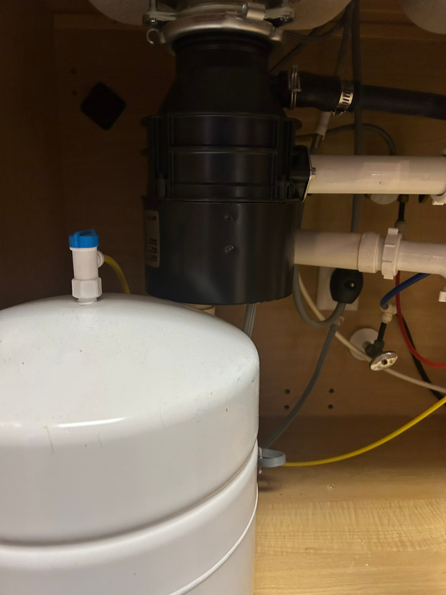 Reverse osmosis storage tank installed beside a garbage disposal under a kitchen sink