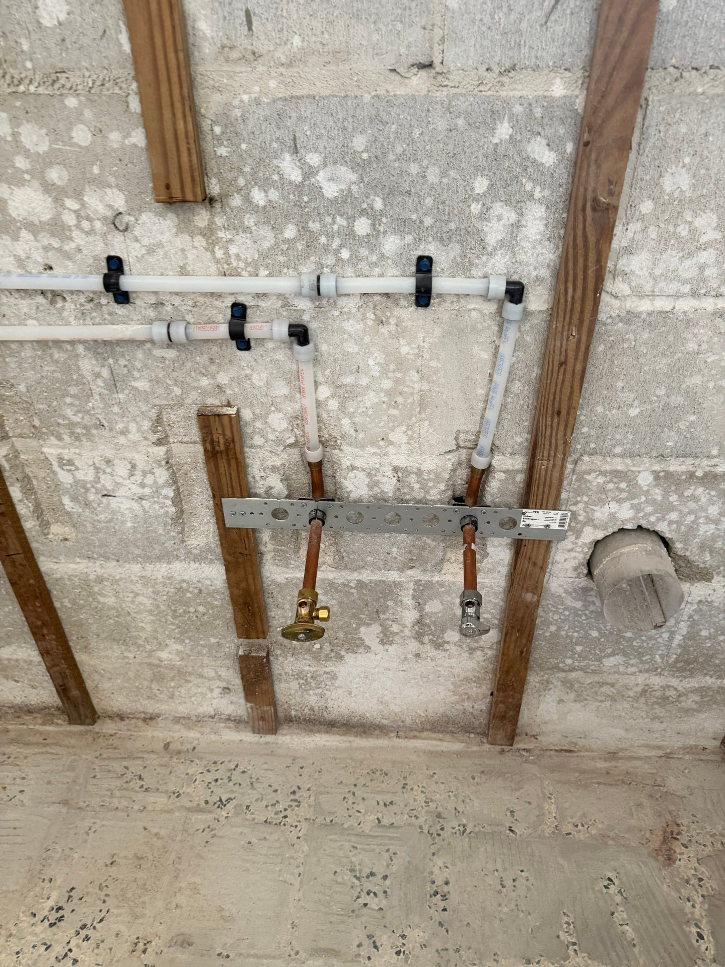 Whole-house repipe rough-in with PEX lines and copper stub-outs supported on a PEX bend support bar