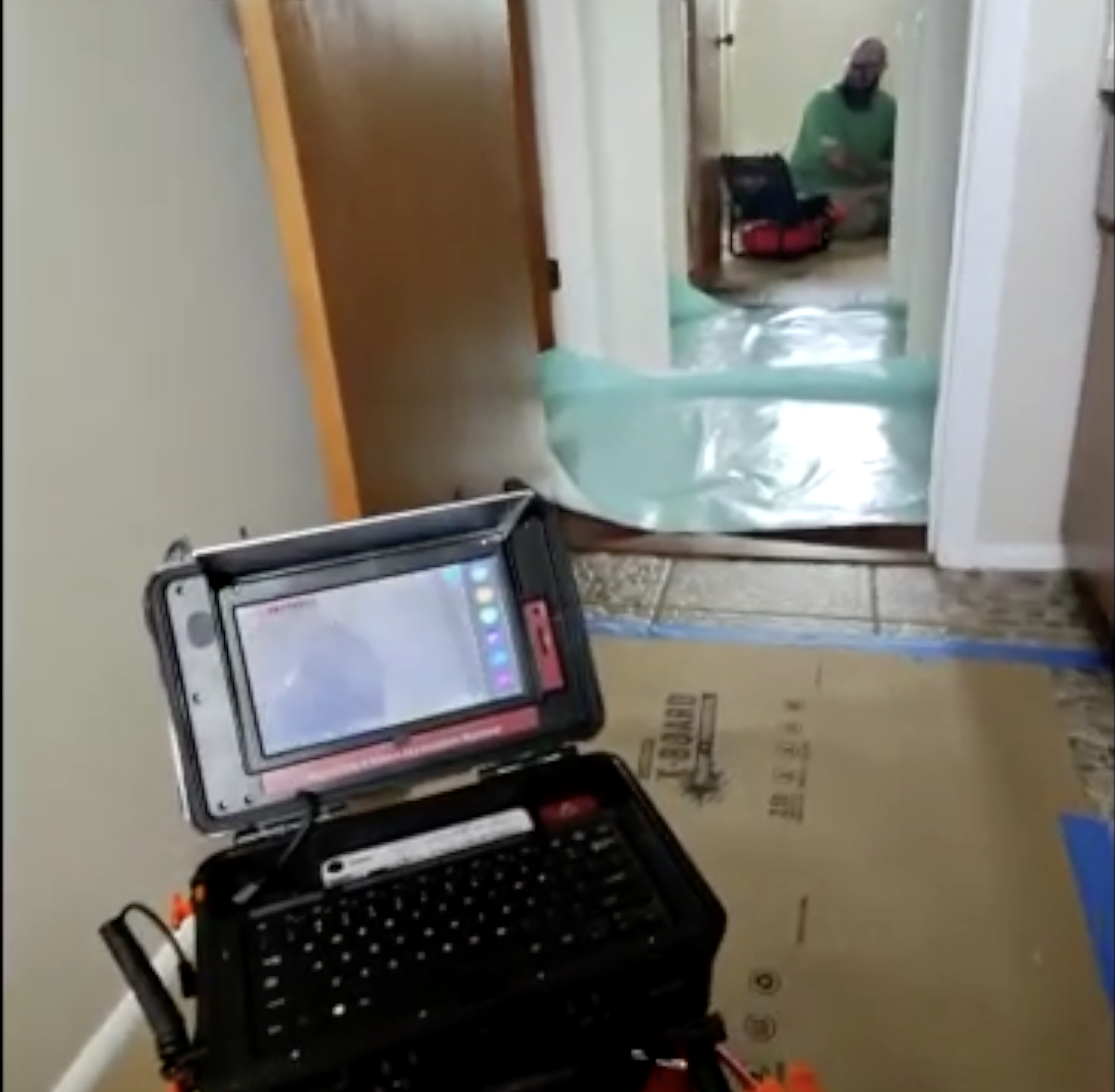 Sewer camera inspection monitor set up on protected floors in a Venice home hallway