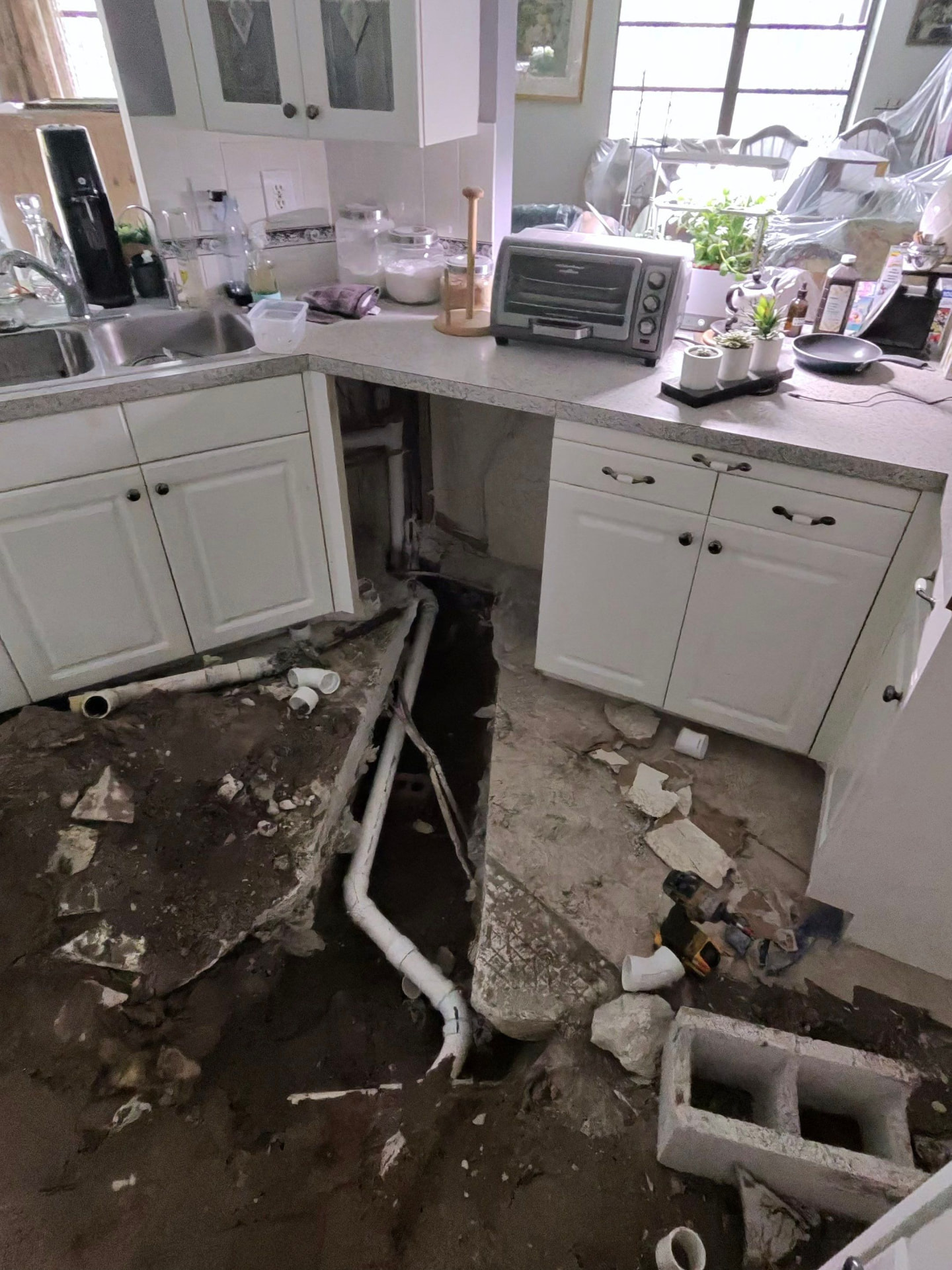 Open kitchen slab trench showing new PVC sewer pipe replacement before backfill