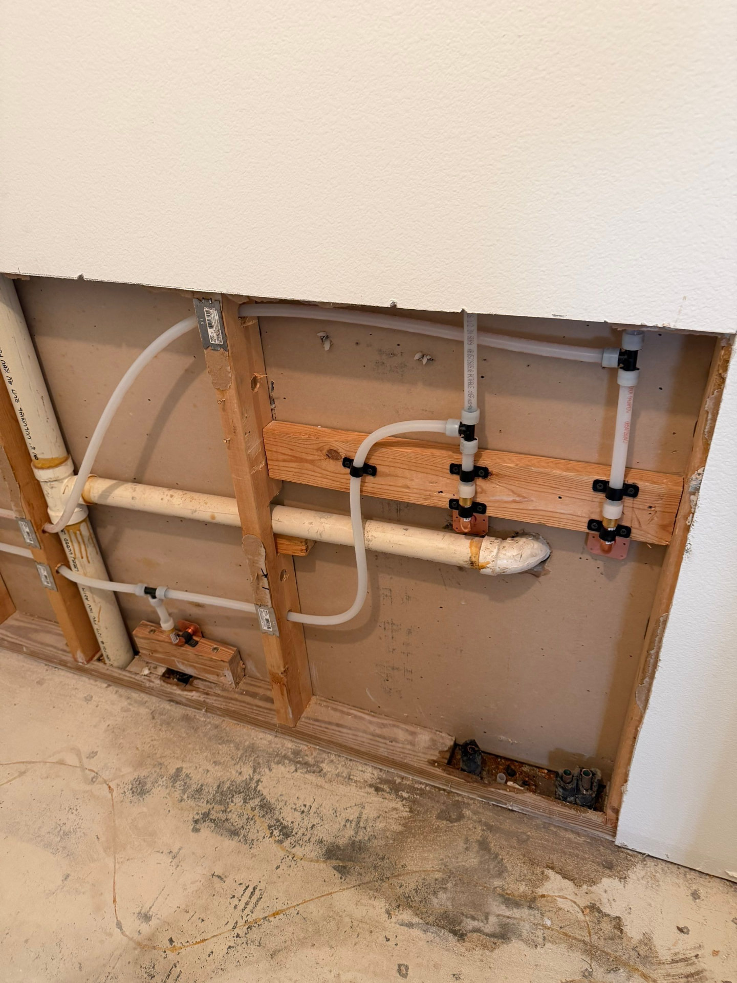 Open interior wall with new PEX branch water lines run alongside original CPVC piping