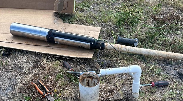 Plumbing tools and pipes on grass during outdoor repair.